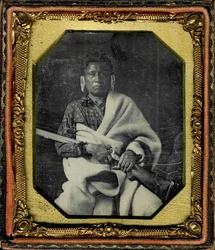 Ritratto di Nacheninga [No Heart of Fear], Iowa. Nacheninga tiene un fucile in mano ed è avvolto in una spessa coperta